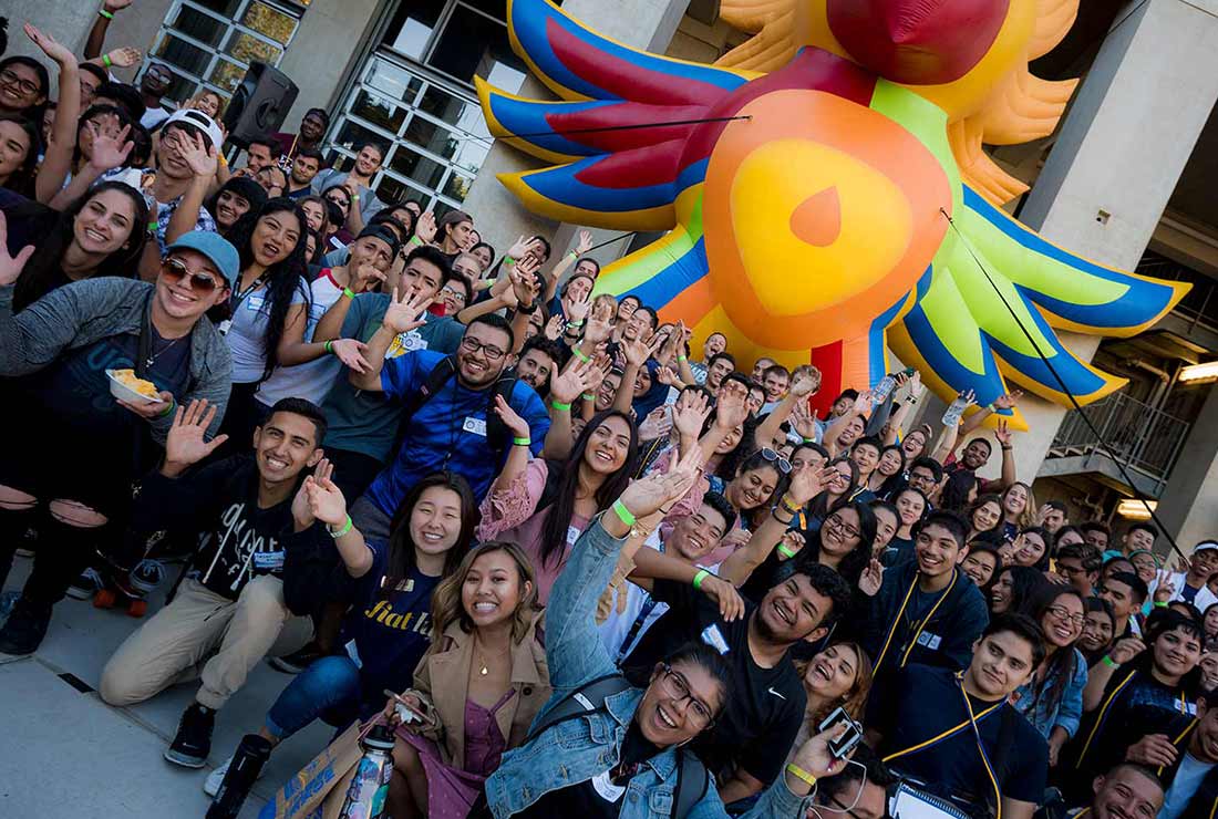 Large group of students cheering in front of a large Sun God blowup balloon